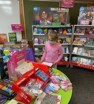Girl looking at books on tables at the Scholastic Book Fair
